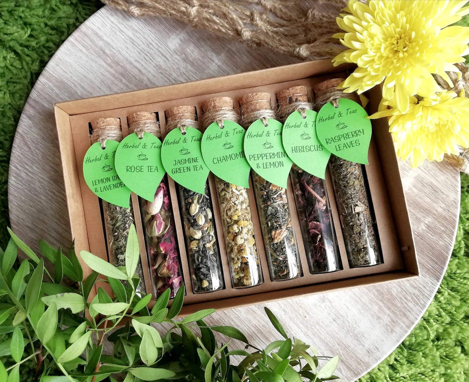 Seven herbal tea tubes with green leaf tags in kraft box